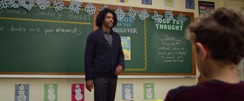Movie still from “Wonder” (2017), directed by Stephen Chbosky – A man standing in front of chalkboards with a smile on his face; Medium shot, Over the shoulder angle