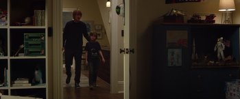 Movie still from “Wonder” (2017), directed by Stephen Chbosky – A man and a boy are walking in a house; Wide shot, Over the shoulder angle