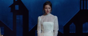 Movie still from “Wonder” (2017), directed by Stephen Chbosky – A woman in a white dress standing in front of a blue wall; Medium shot, Over the shoulder angle
