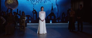 Movie still from “Wonder” (2017), directed by Stephen Chbosky – A woman in a white dress standing on a stage; Wide shot, High angle