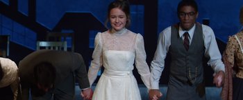 Movie still from “Wonder” (2017), directed by Stephen Chbosky – A young woman in a white dress holding hands with a man; Medium shot, Over the shoulder angle