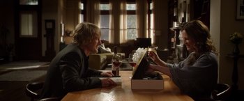 Movie still from “Wonder” (2017), directed by Stephen Chbosky – Two people sitting at a wooden table with a wine glass; Medium shot, Over the shoulder angle