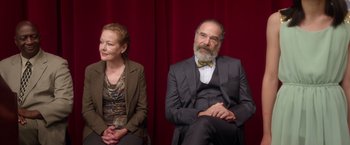 Movie still from “Wonder” (2017), directed by Stephen Chbosky – A man and a woman sitting next to each other in front of a red curtain; Medium shot, High angle