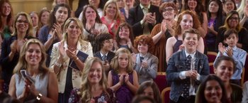 Movie still from “Wonder” (2017), directed by Stephen Chbosky – A group of people sitting in front of an audience clapping; Medium shot, High angle