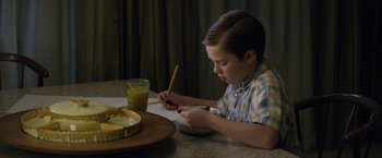 Movie still from “Woodlawn” (2015), directed by Jon Erwin – A young boy is writing on a bowl of cereal; Medium shot, High angle