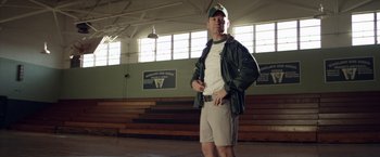 Movie still from “Woodlawn” (2015), directed by Jon Erwin – A man standing in front of bleachers in a gymnasium; Medium shot, Low angle
