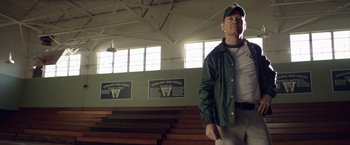 Movie still from “Woodlawn” (2015), directed by Jon Erwin – A man in a baseball uniform standing in front of bleachers; Medium shot, Low angle