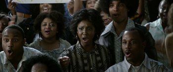 Movie still from “Woodlawn” (2015), directed by Jon Erwin – A group of people standing in a room; Medium shot, Over the shoulder angle