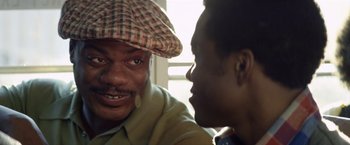 Movie still from “Woodlawn” (2015), directed by Jon Erwin – A man wearing a plaid hat talking to another man; Close Up shot, Over the shoulder angle