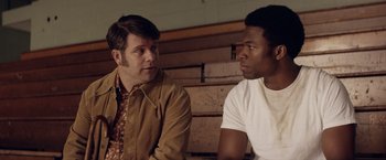 Movie still from “Woodlawn” (2015), directed by Jon Erwin – Two men sitting next to each other in front of a wooden wall; Close Up shot, Over the shoulder angle