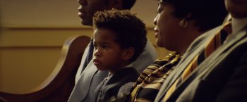 Movie still from “Woodlawn” (2015), directed by Jon Erwin – A young boy sitting in front of two other people; Close Up shot, Over the shoulder angle