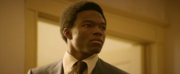 Movie still from “Woodlawn” (2015), directed by Jon Erwin – A man in a suit and tie looking to his left; Close Up shot, Low angle
