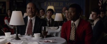 Movie still from “Woodlawn” (2015), directed by Jon Erwin – A group of people sitting at a table with wine glasses; Medium shot, Over the shoulder angle