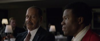 Movie still from “Woodlawn” (2015), directed by Jon Erwin – A man in a suit and tie next to another man in a suit and tie; Close Up shot, Over the shoulder angle