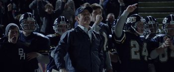 Movie still from “Woodlawn” (2015), directed by Jon Erwin – A group of men standing next to each other on top of a football field; Medium shot, Low angle