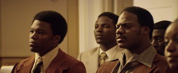 Movie still from “Woodlawn” (2015), directed by Jon Erwin – A group of men in suits and ties standing next to each other; Medium shot, Low angle