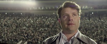 Movie still from “Woodlawn” (2015), directed by Jon Erwin – A person wearing a suit and tie; Close Up shot, Over the shoulder angle
