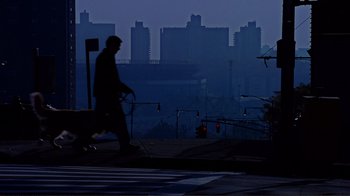 Movie still from “World Trade Center” (2006), directed by Oliver Stone – A man walking a dog on a leash in front of a city skyline; Extreme Wide shot, Low angle