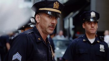 Movie still from “World Trade Center” (2006), directed by Oliver Stone – A man in a police officer's uniform and hat; Close Up shot, Over the shoulder angle
