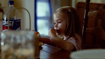 Movie still from “World Trade Center” (2006), directed by Oliver Stone – A little girl sitting at a table eating a cupcake; Close Up shot, Over the shoulder angle