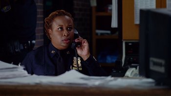 Movie still from “World Trade Center” (2006), directed by Oliver Stone – A police officer talking on a phone in a room; Medium shot, Over the shoulder angle