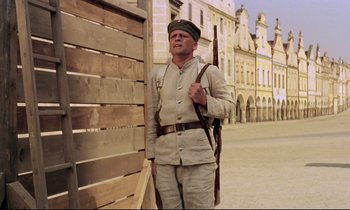 Movie still from “Woyzeck” (1979), directed by Werner Herzog – A man in a military uniform standing next to a building; Wide shot, Low angle