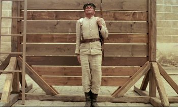 Movie still from “Woyzeck” (1979), directed by Werner Herzog – A man dressed as a soldier holding a rifle; Wide shot, Low angle