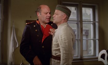 Movie still from “Woyzeck” (1979), directed by Werner Herzog – Two men in military uniforms one of which is holding a red scarf; Medium shot, Low angle