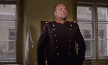 Movie still from “Woyzeck” (1979), directed by Werner Herzog – A man in a military uniform standing in front of a window; Medium shot, Low angle