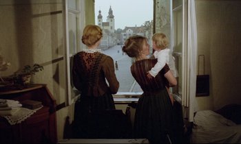 Movie still from “Woyzeck” (1979), directed by Werner Herzog – Two women and a child looking out a window; Wide shot, Over the shoulder angle