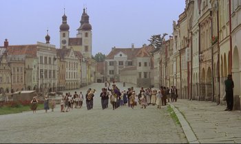 Movie still from “Woyzeck” (1979), directed by Werner Herzog – A group of people walking down a street near buildings; Extreme Wide shot, High angle