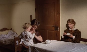 Movie still from “Woyzeck” (1979), directed by Werner Herzog – A woman holding a child near a table with a cup of coffee; Medium shot, High angle