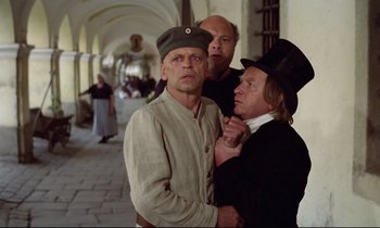Movie still from “Woyzeck” (1979), directed by Werner Herzog – A group of men standing next to each other in a hallway; Medium shot, Over the shoulder angle
