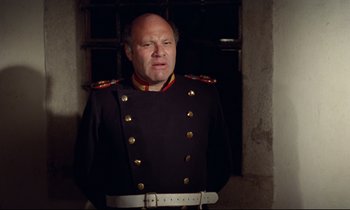 Movie still from “Woyzeck” (1979), directed by Werner Herzog – A man in a military uniform standing in front of a window; Medium shot, Low angle