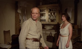 Movie still from “Woyzeck” (1979), directed by Werner Herzog – A man and a woman standing next to each other in a kitchen; Medium shot, Low angle