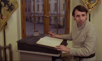 Movie still from “Woyzeck” (1979), directed by Werner Herzog – A man sitting at a table writing on a piece of paper; Medium shot, High angle