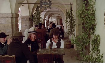 Movie still from “Woyzeck” (1979), directed by Werner Herzog – A group of people sitting at a table in a restaurant; Wide shot, High angle