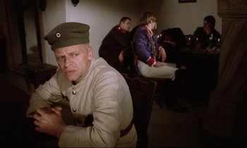 Movie still from “Woyzeck” (1979), directed by Werner Herzog – A group of people sitting in a room; Medium shot, Low angle