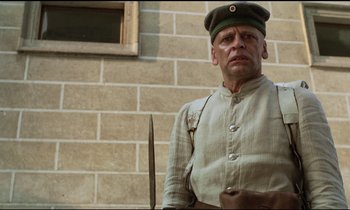 Movie still from “Woyzeck” (1979), directed by Werner Herzog – A man in a military uniform holding a sword; Medium shot, Low angle