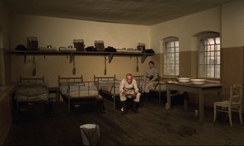 Movie still from “Woyzeck” (1979), directed by Werner Herzog – Two men sitting on a bed in a room; Wide shot, High angle