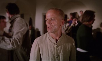 Movie still from “Woyzeck” (1979), directed by Werner Herzog – A man in a tan jacket is looking at the camera; Medium shot, Low angle