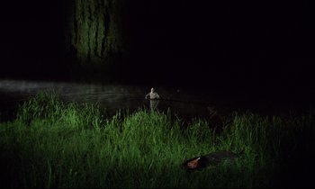 Movie still from “Woyzeck” (1979), directed by Werner Herzog – A man standing next to a dead body in the grass; Extreme Wide shot, High angle