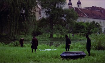 Movie still from “Woyzeck” (1979), directed by Werner Herzog – Two people standing in the grass near a body of water; Extreme Wide shot, High angle