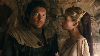 Movie still from “Wrath of the Titans” (2012), directed by Jonathan Liebesman – A man and a woman standing next to each other in front of a brick wall; Close Up shot, Low angle