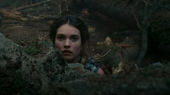 Movie still from “Wrath of the Titans” (2012), directed by Jonathan Liebesman – A young woman is looking at the camera while standing in the woods; Close Up shot, High angle