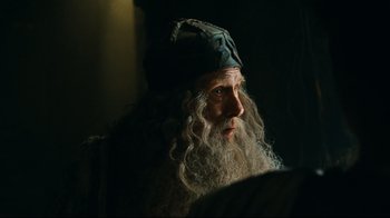 Movie still from “Wrath of the Titans” (2012), directed by Jonathan Liebesman – A man with long white hair and a beard wearing a hat; Close Up shot, Over the shoulder angle