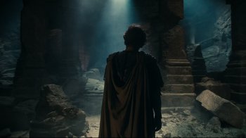 Movie still from “Wrath of the Titans” (2012), directed by Jonathan Liebesman – A man wearing a robe and standing in a cave; Wide shot, High angle