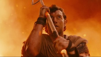 Movie still from “Wrath of the Titans” (2012), directed by Jonathan Liebesman – A man holding a baseball bat in front of a fire background; Close Up shot, Low angle