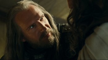 Movie still from “Wrath of the Titans” (2012), directed by Jonathan Liebesman – A man with long hair and a goatee looking at a woman with long hair; Close Up shot, Over the shoulder angle