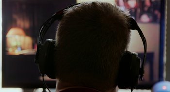 Movie still from “Wrinkles the Clown” (2019), directed by Michael Beach Nichols – A man with a beard and headphones on; Extreme Close Up shot, Over the shoulder angle